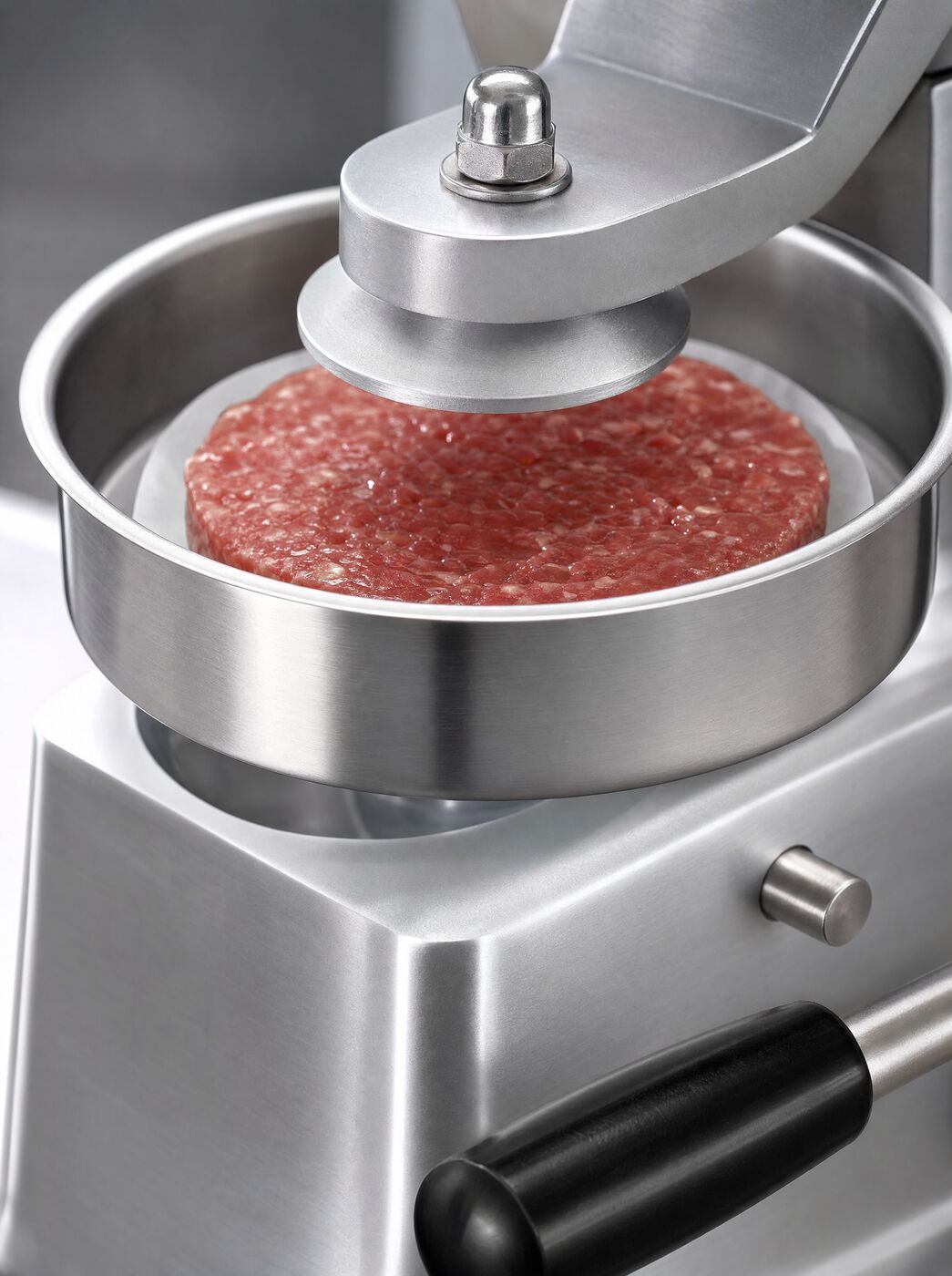 Close view of a freshly pressed patty in the stainless tray