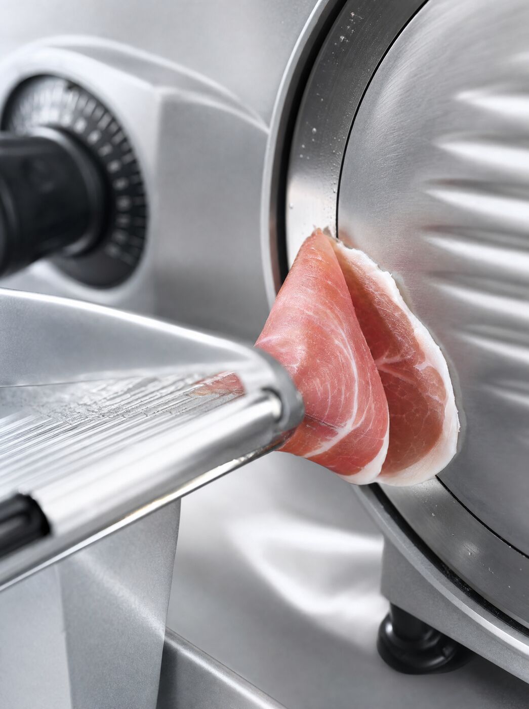 Close view of the blade edge with a slice of prosciutto parting from it