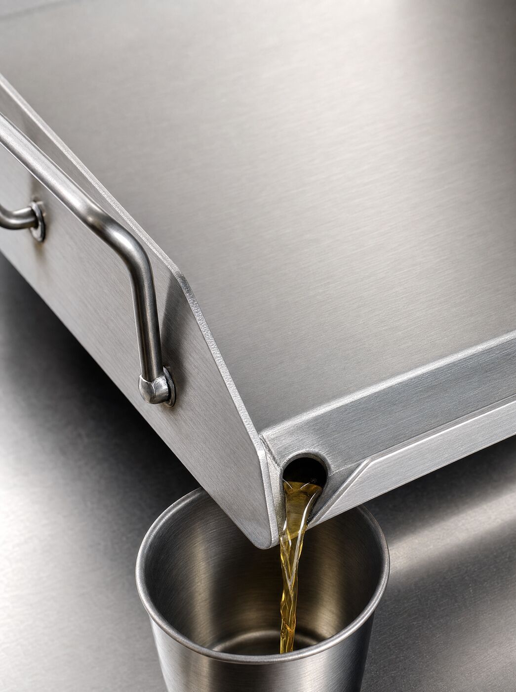 Close view of the grease trough and drip hole draining into a cup