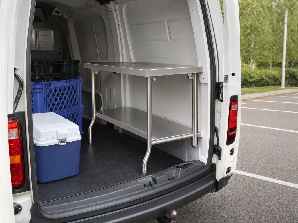 The table half folded in the back of a van beside crates