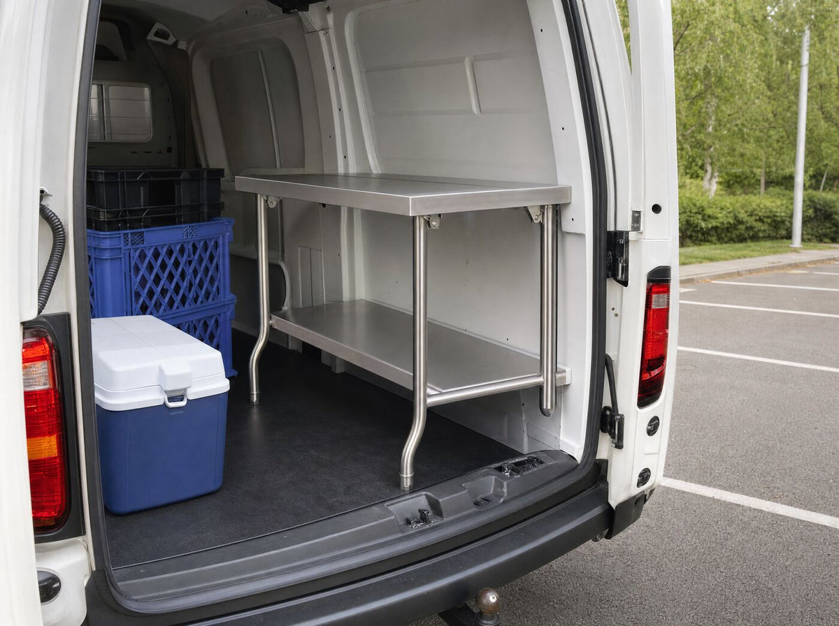 The table half folded in the back of a van beside crates