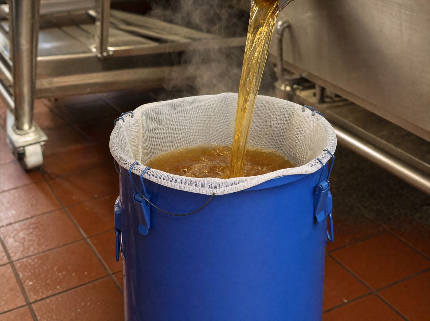 Fryer oil pouring through the filter bag into the open caddy